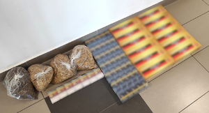 krajanka tytoniu w czterech foliowych workach, obok papierosy w paczkach i kartony z papierosami