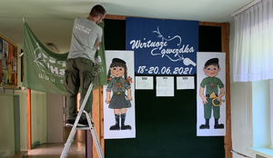 mężczyzna stojący na drabinie rozwiesza baner hufca