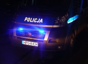 noc, fragment radiowozu z włączonymi niebieskimi światłami