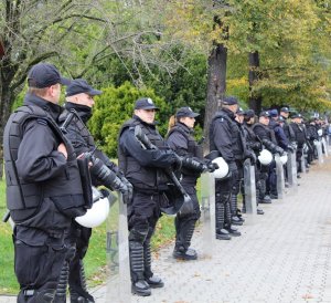 policjanci w pełnym umundurowaniu z tarczami podczas zabezpieczenia marszu