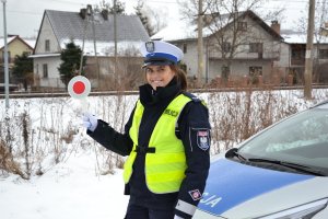 policjantka ruchu drogowego z tarczą do zatrzymywania pojazdów stojąca przy radiowozie