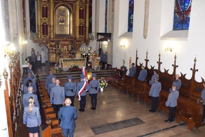 widok na ołtarz oraz ławki, przy których stoją policjanci