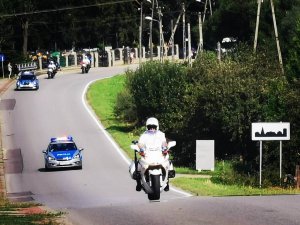 9. policjant na motocyklu w tle dwa radiowozy- pilotaż wyścigu