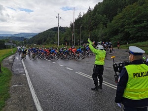 grupa kolarzy, obok policjant kieruje ruchem