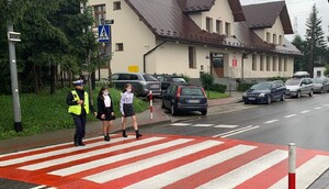 policjantka ruchu drogowego przeprowadza uczennice przez przejście dla pieszych