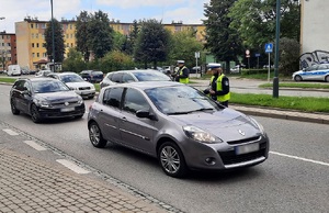 dwójka policjantów rozdaje kierowcom ulotki i elementy odblaskowe