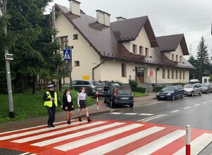 policjantka ruchu drogowego przeprowadza uczennice przez przejście dla pieszych