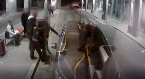 dworzec autobusowy, policjanci prowadzą zatrzymanego mężczyznę do nieoznakowanego radiowozu