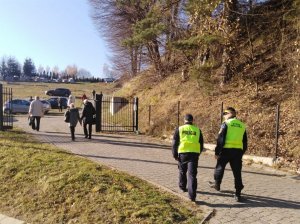 policjant i strażnik miejski patrolują teren cmentarza