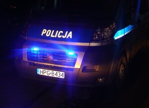 noc, fragment radiowozu z włączonymi niebieskimi światłami