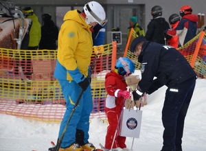 policjant wręcza odblask małemu narciarzowi