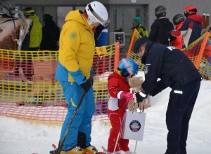 policjant wręcza odblask małemu narciarzowi