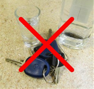 kluczyki do samochodu, obok butelka i kieliszek z alkoholem - przekreślone czerwonym X