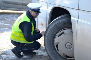 policjant ruchu drogowego kontroluje stan techniczny autobusu
