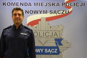 kom. Jakub Mółka na tle banneru sądeckiej Policji