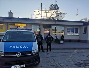 Dwóch umundurowanych policjantów patroluje dworzec autobusowy