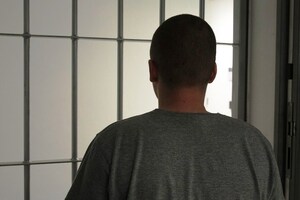 mężczyzna stojący przed kratami