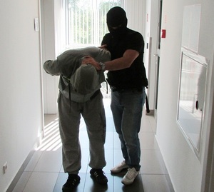 policjant prowadzi zatrzymanego mężczyznę