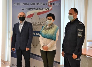 wspólne zdjęcie na tle banneru sądeckiej Policji - od prawej komendant, dyrektor szkoły i nauczyciel