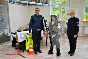 policjantka i policjant oraz chłopiec z policyjną tarczą i sprzętem wykorzystywanym przez policjantów prewencji