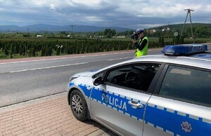 radiowóz, obok policjant z laserowym miernikiem prędkości