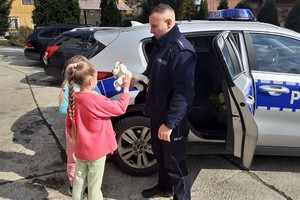 policjant przekazuje dziewczynce maskotkę — kopia