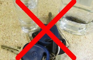 kluczyki do samochodu, obok butelka i kieliszek z alkoholem - przekreślone czerwonym X -