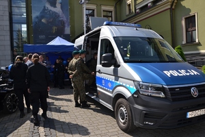 oznakowany radiowóz na dziedzińcu MCK Sokół obok osoby przyglądające się z bliska policyjnemu sprzętowi