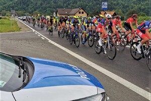 jadący zawodnicy, obok policyjny radiowóz