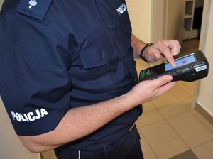 policjant dotyka palcem ekranu dotykowego analizatora