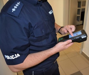 policjant dotyka palcem ekranu dotykowego analizatora narkotyków