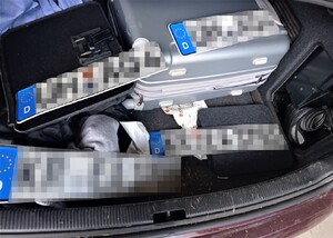 wnętrze bagażnika audi - cztery tablice rejestracyjne, walizki, odzież