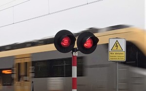 sygnalizator nadający światło czerwone, w tle przejeżdżający pociąg