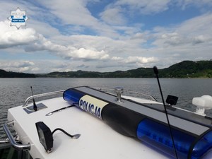 fragment policyjnej łodzi, w tle Jezioro Rożnowskie