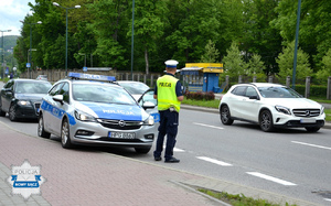 samochody na ulicy, policyjny radiowóz, obok policjant ruchu drogowego