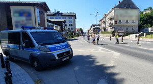 centrum Krynicy-Zdroju, biegacze, umundurowany policjant ruchu drogowego, obok radiowóz