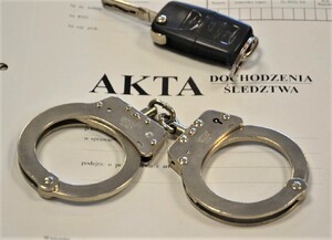kajdanki oraz kluczyk do samochodu położone na okładce akt