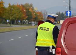 kontrola drogowa - policjant w odblaskowej kamizelce, obok czerwony samochód