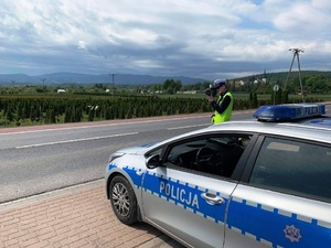 radiowóz, obok policjant z laserowym miernikiem prędkości