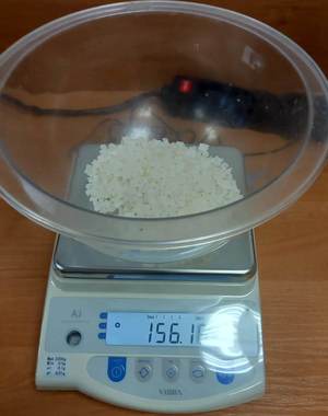 waga elektroniczna ze szklanym pojemnikiem w którym znajdują się białe kryształki- narkotyk
