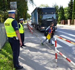 dwóch uczniów przechodzi przez przejście dla pieszych, obok policjanci sądeckiej drogówki - zdjęcie archiwalne