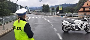 policjantka ruchu drogowego, obok motocykl służbowy, w tle biegnący zawodnicy