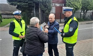 16. policjanci i dyrektor MORD wręczają odbaski i drobny upominek pieszej