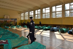12. policjant w sali gimnastycznej, obok leżaki z chorymi