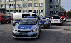 pojazdy służb zaparkowane przed budynkiem szkoły