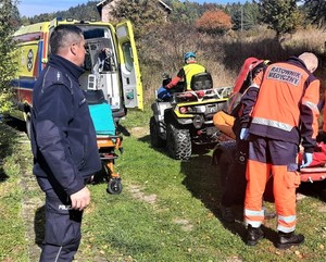 policjant i ratownik medyczny, sprawdzany jest stan poszkodowanego,w tle karetka pogotowia ratunkowego