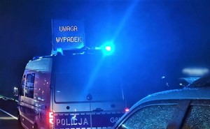 noc, policyjny radiowóz, błyskające lampy, na dachu radiowozu napis Uwaga wypadek