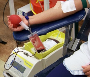 akcja krwiodawstwa - fragment kobiecej ręki ściskającej czerwone serduszko, krew spływa do specjalnego woreczka