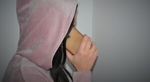 kobieta w różowej bluzie z kapturem na głowie, rozmawia przez telefon komórkowy - zdjęcie ilustracyjne — kopia