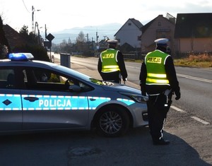 umundurowani policjanci ruchu drogowego przy drodze, obok radiowóz